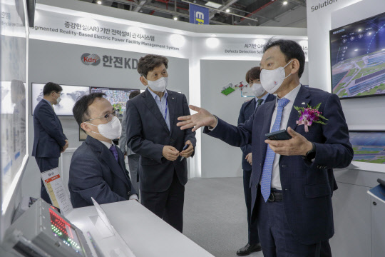 한전KDN은 '2022 대한민국 전기산업엑스포'에 참가했다고 14일 밝혔다. 사진은 엑스포 부스에서 설명을 듣고 있는 김장현 한전KDN 사장(오른쪽). <한전KDN>